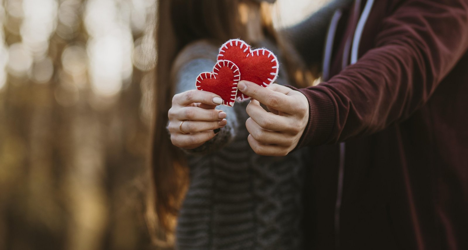 Pár milencov drží na Valentína v rukách dve červené srdcia